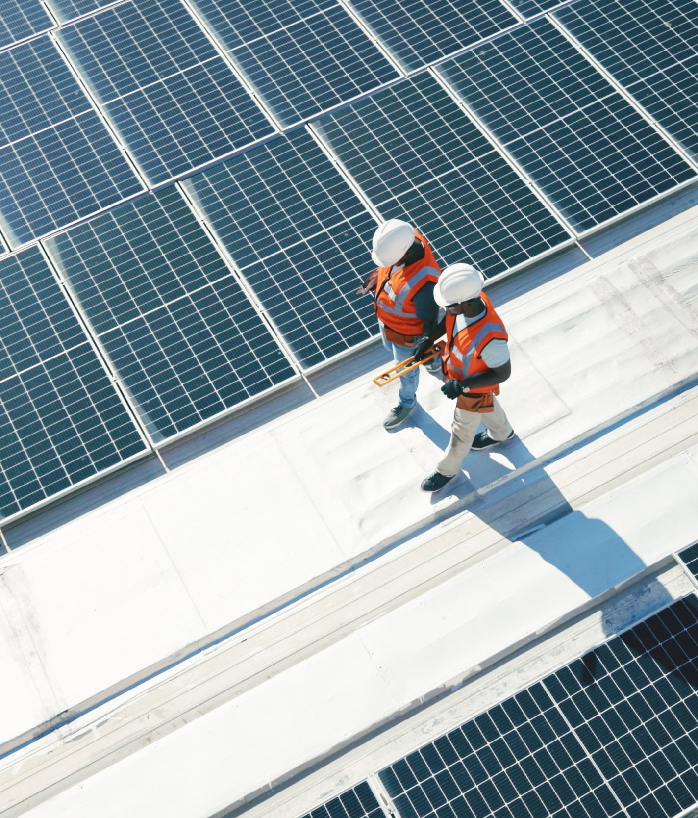 Two technicians installing solar panels on a roof